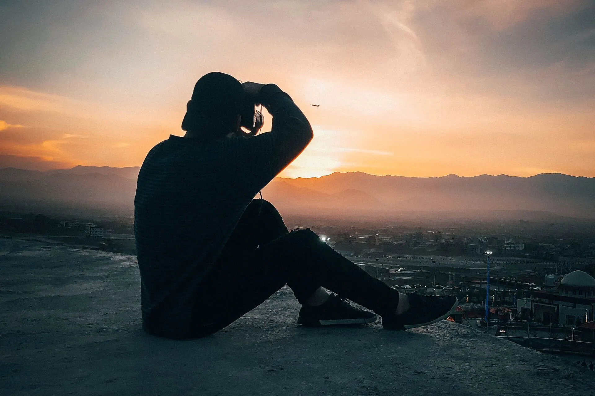 A person looking across a city from a rooftop at sunset