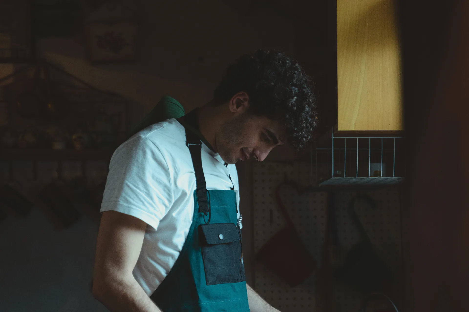 A cook plating food in a dimly lit kitchen