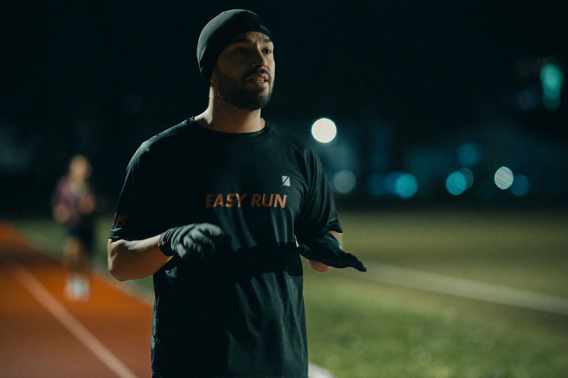 A runner training on a floodlit track at night